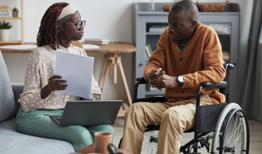 Portrait of African-American couple with handicapped man using wheelchair working from home together in modern interior